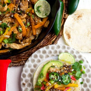 A plate topped with a chicken fajita is placed next to a skillet.