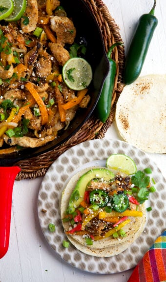 A plate topped with a chicken fajita is placed next to a skillet.
