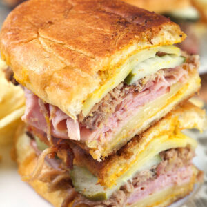 A halved Cuban sandwich is stacked on a plate.