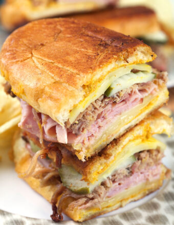 A halved Cuban sandwich is stacked on a plate.