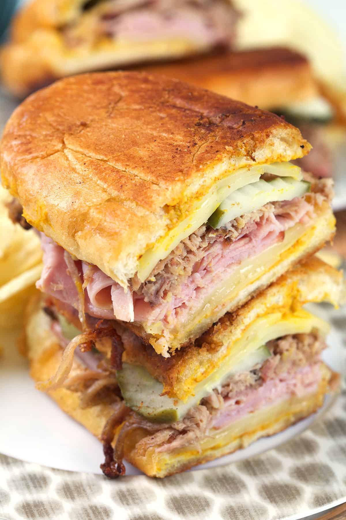 A halved Cuban sandwich is stacked on a plate. 