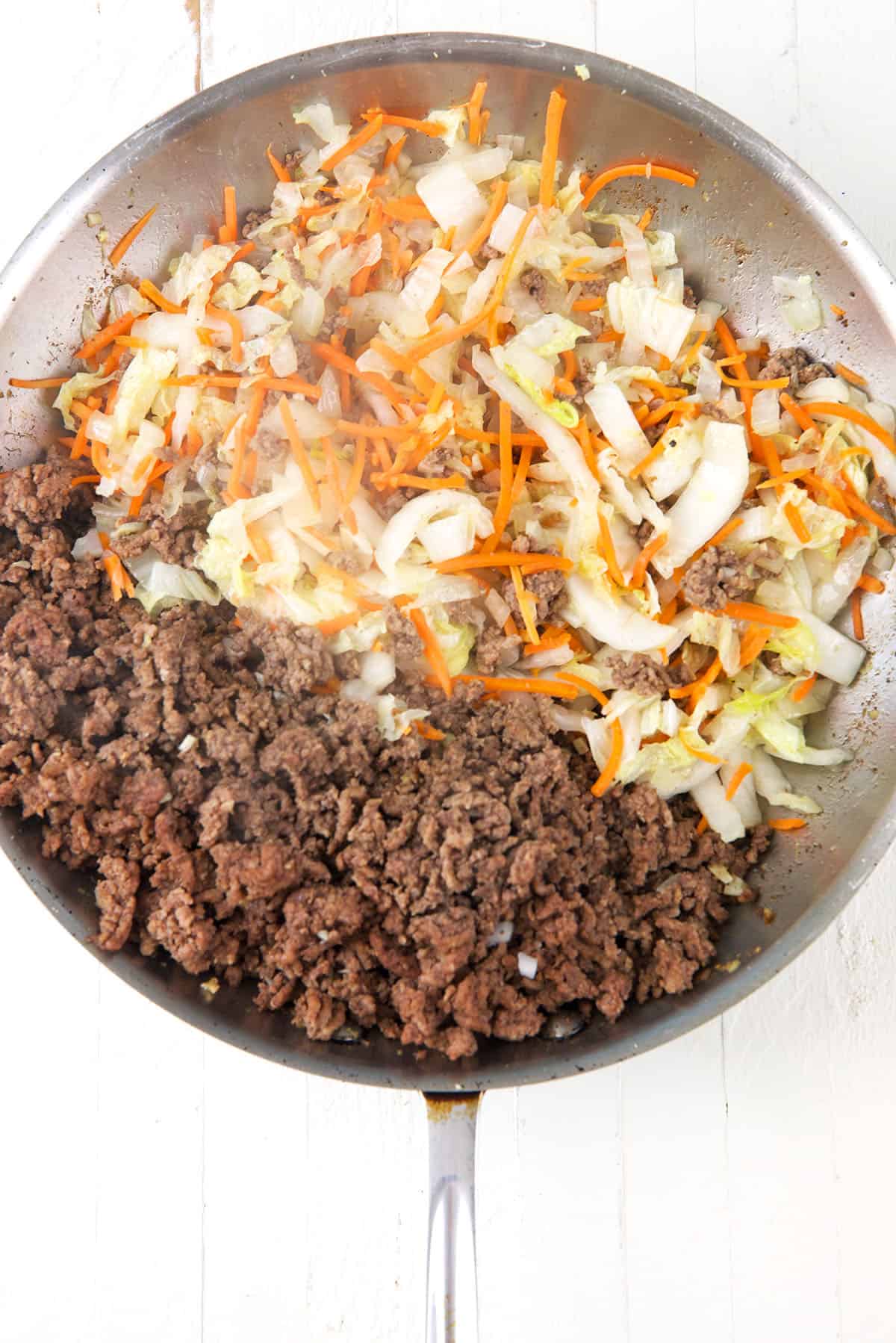 Veggies and ground beef are in a skillet. 