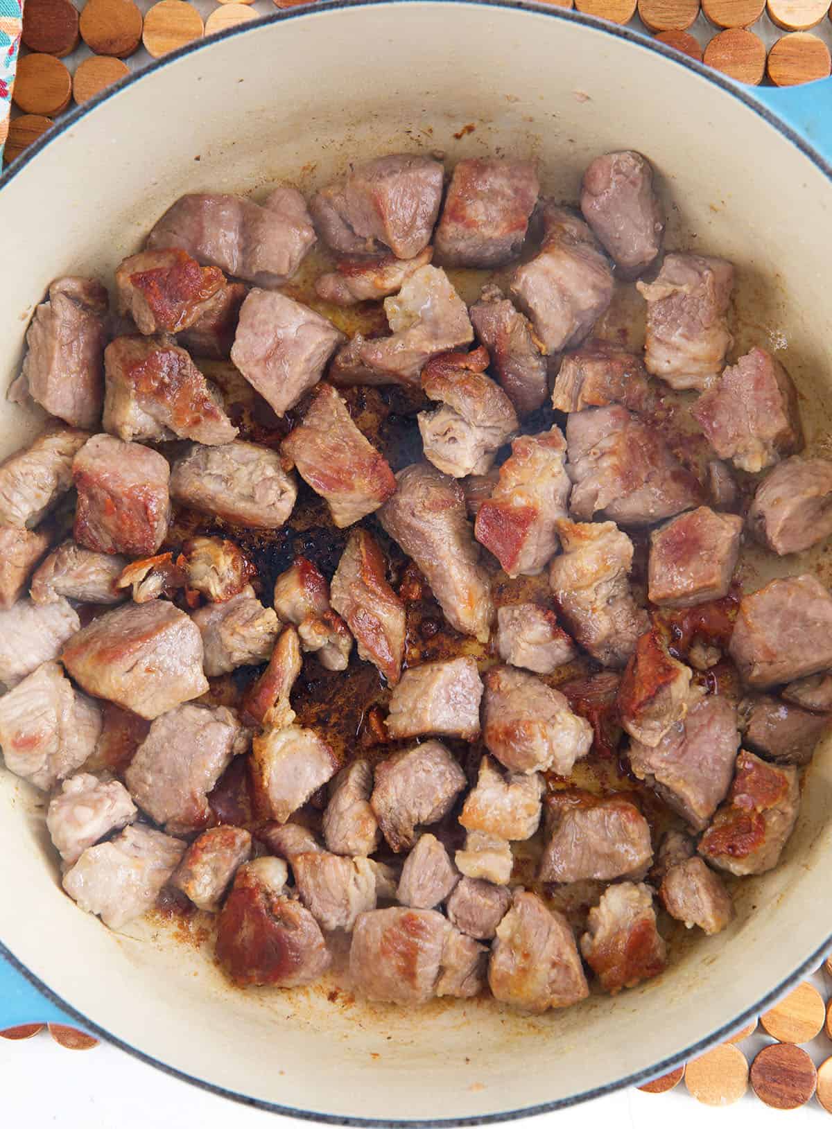 Pork is being seared in a pot. 
