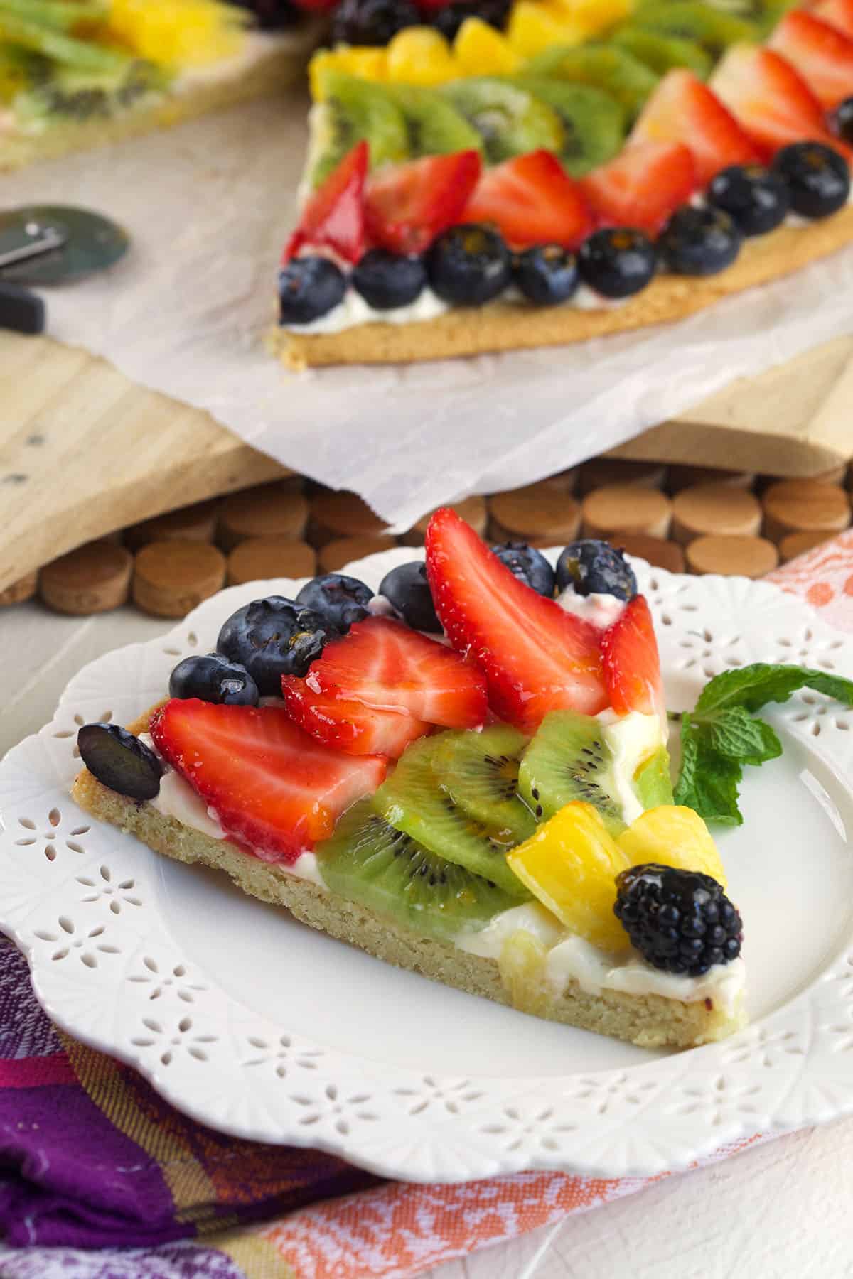 A slice of fruit pizza is on a white plate. 