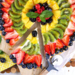 A slice of fruit pizza has been removed from the whole thing.