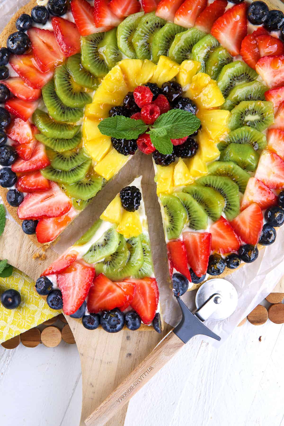 A slice of fruit pizza has been removed from the whole thing. 
