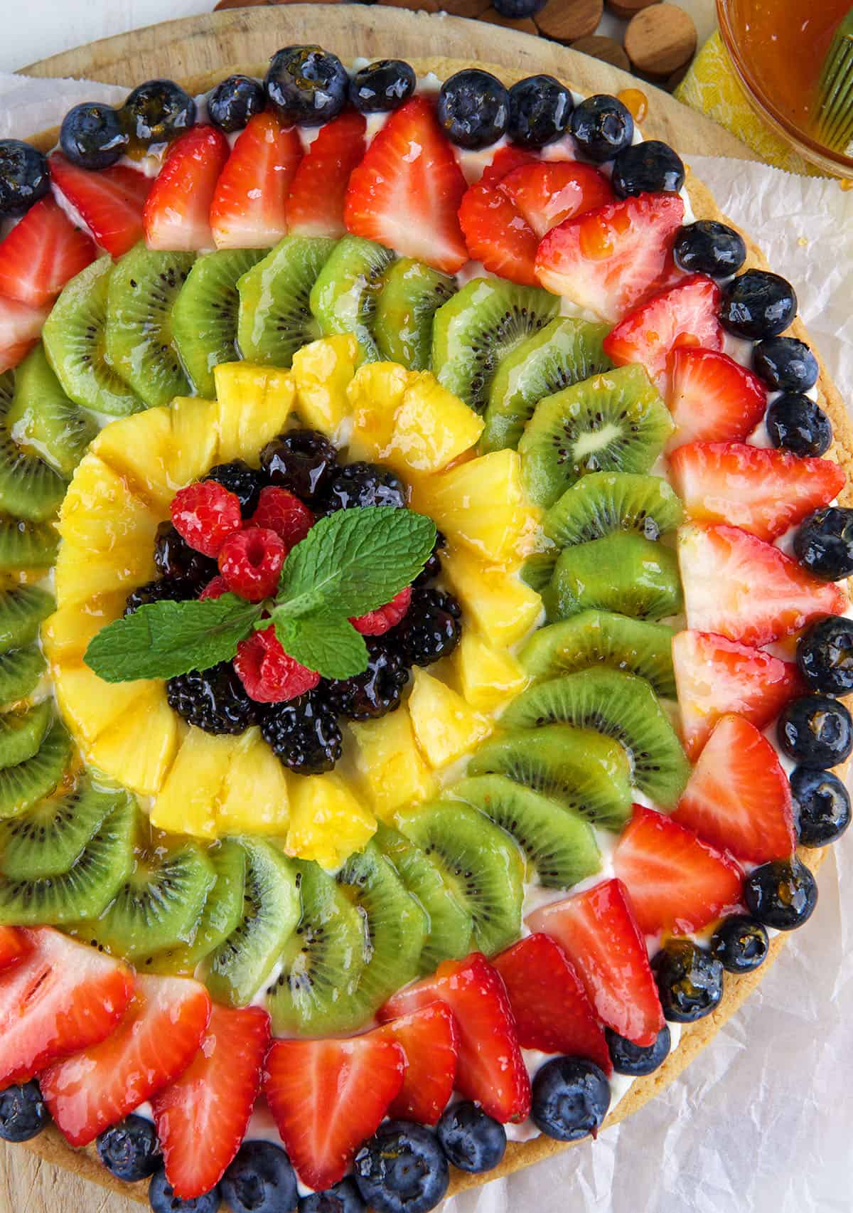 A whole fruit pizza is presented with no slices cut. 
