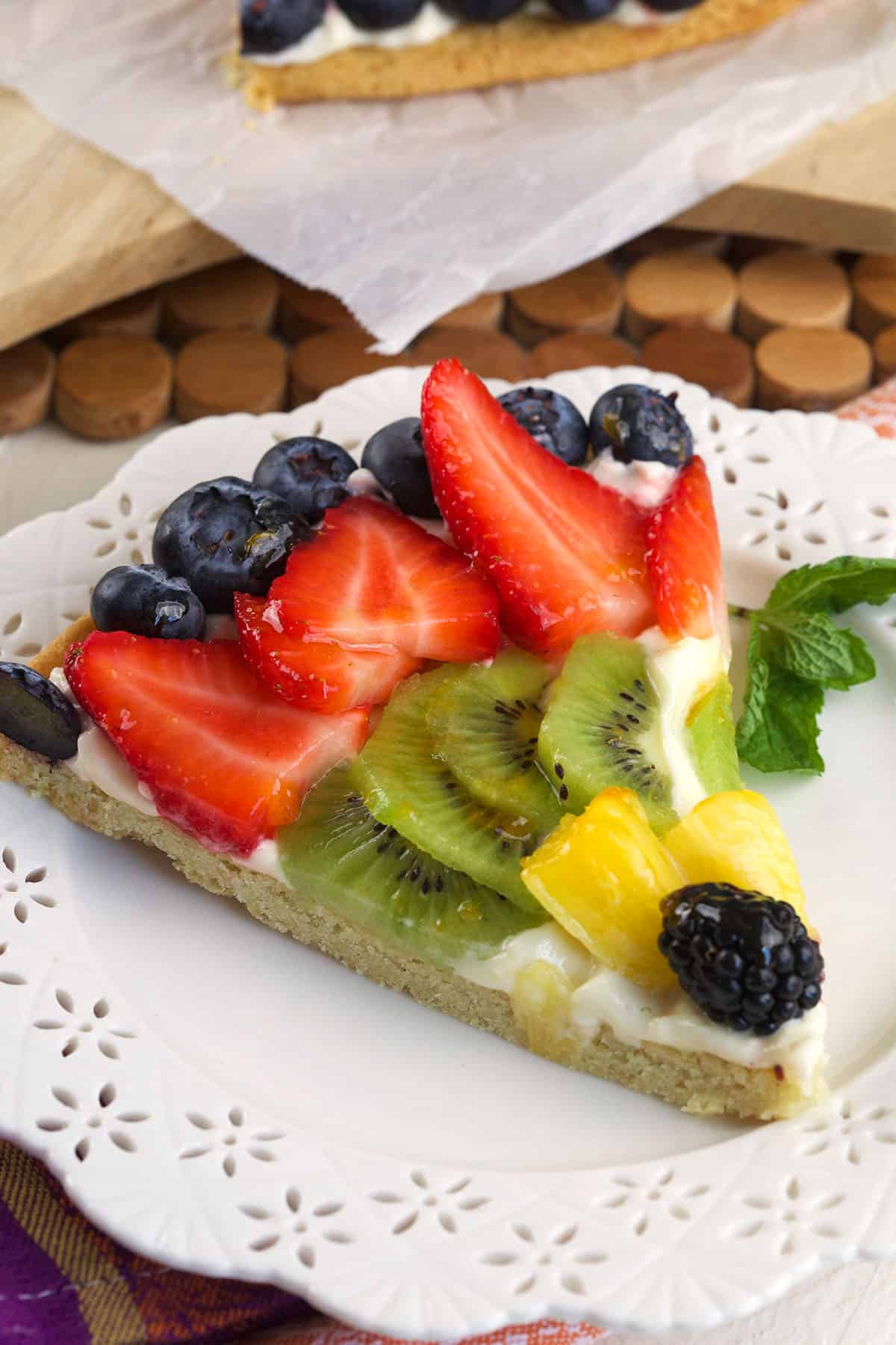 A slice of fruit pizza is on a white plate.