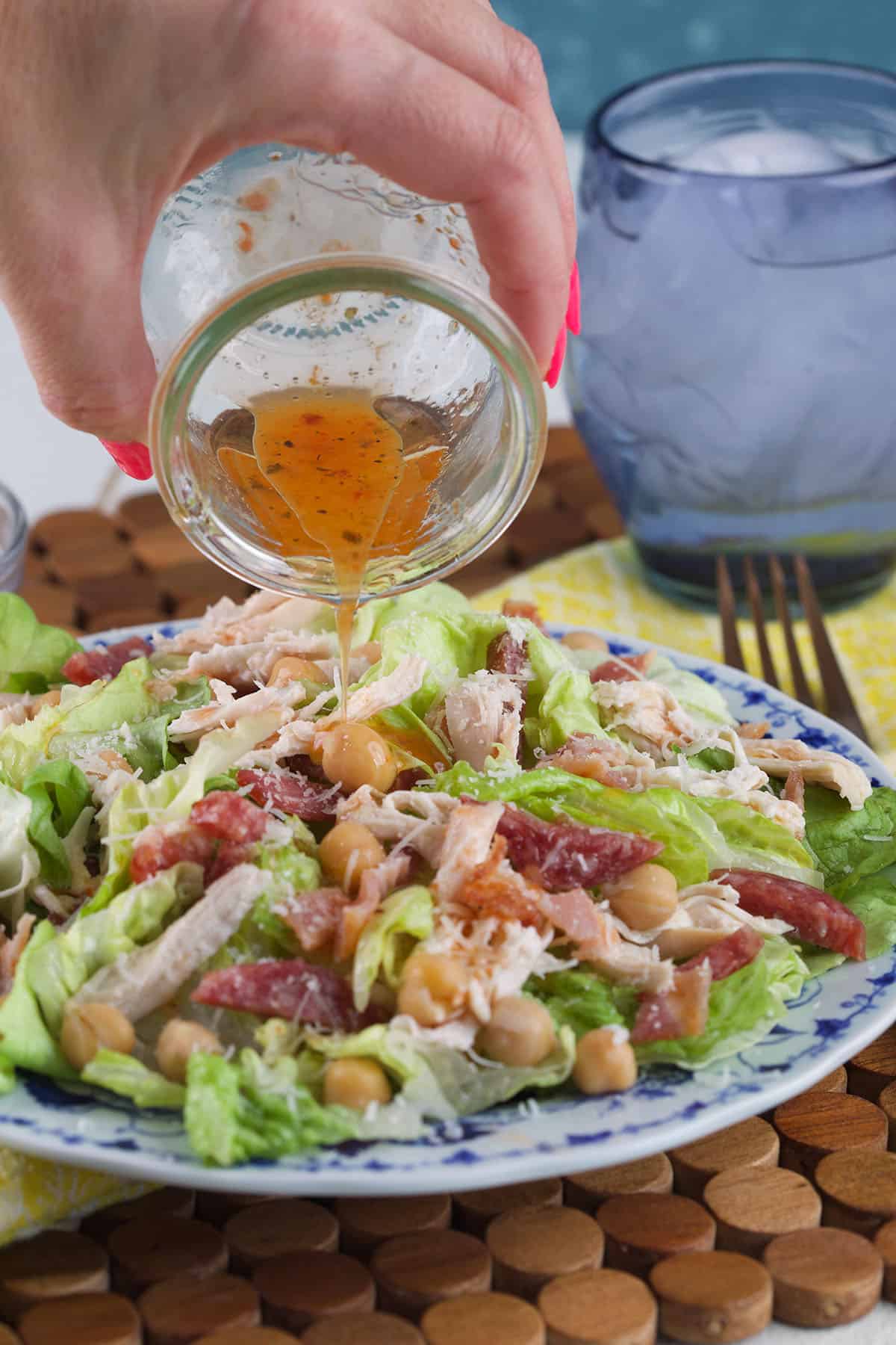 Dressing is being poured on top of a tossed salad.