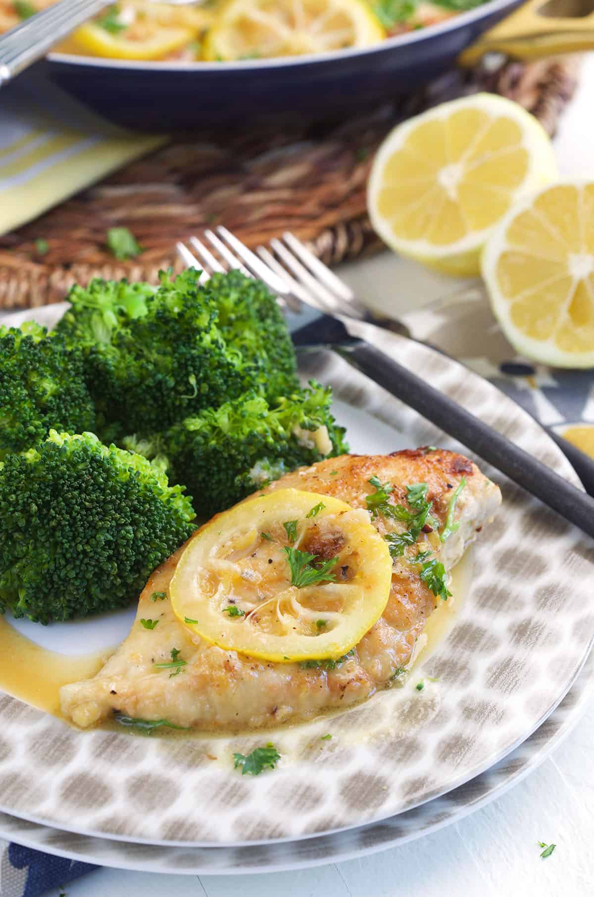 Lemon pepper chicken is plated with broccoli. 