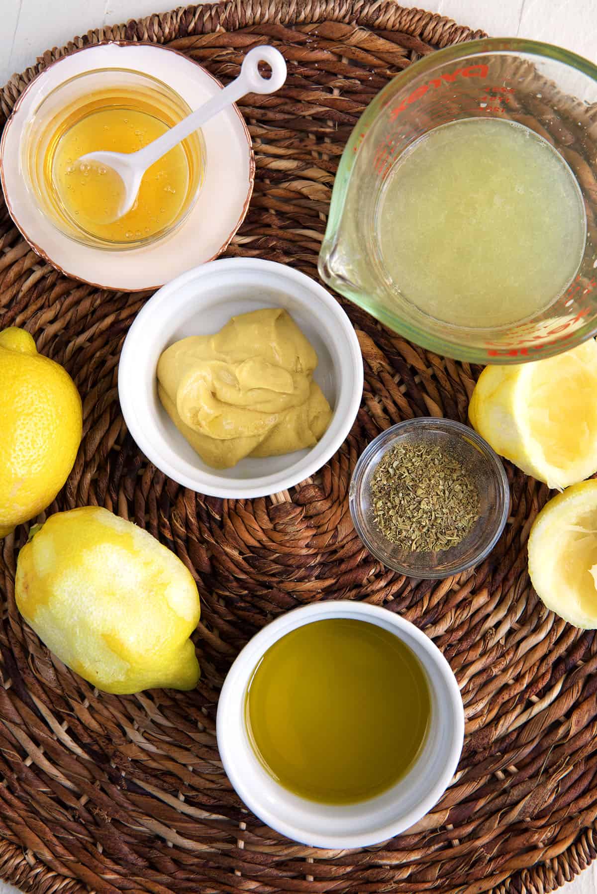 The ingredients for lemon vinaigrette are on a woven place mat. 