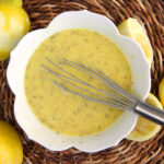 A whisk is stirring the ingredients together in a white bowl.