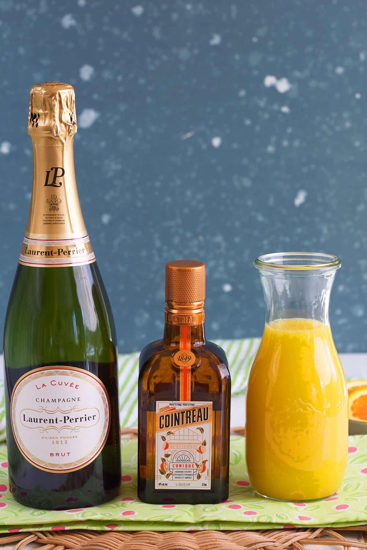 The ingredients for mimosas are placed on a green surface. 