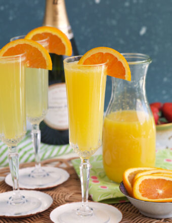 Oranges garnish several glasses of mimosas.