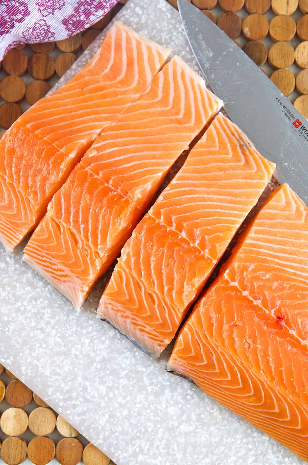 A whole salmon filet is cut into several pieces. 