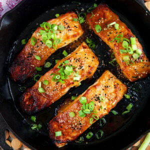 Fully cooked salmon filets are in a skillet.