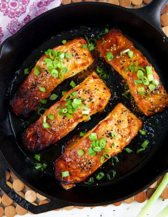 Fully cooked salmon filets are in a skillet.