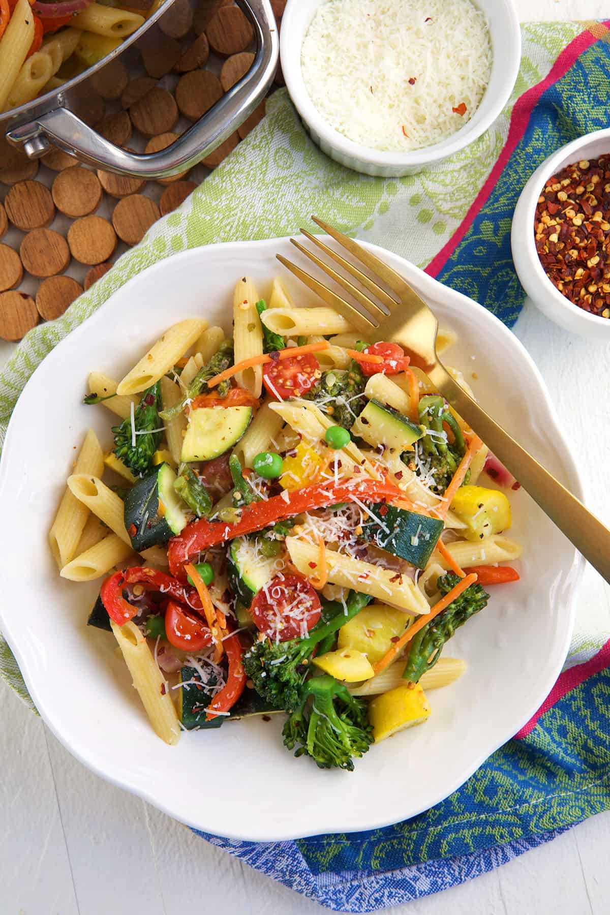 Pasta Primavera plated in a white pasta bowl with a gold fork.