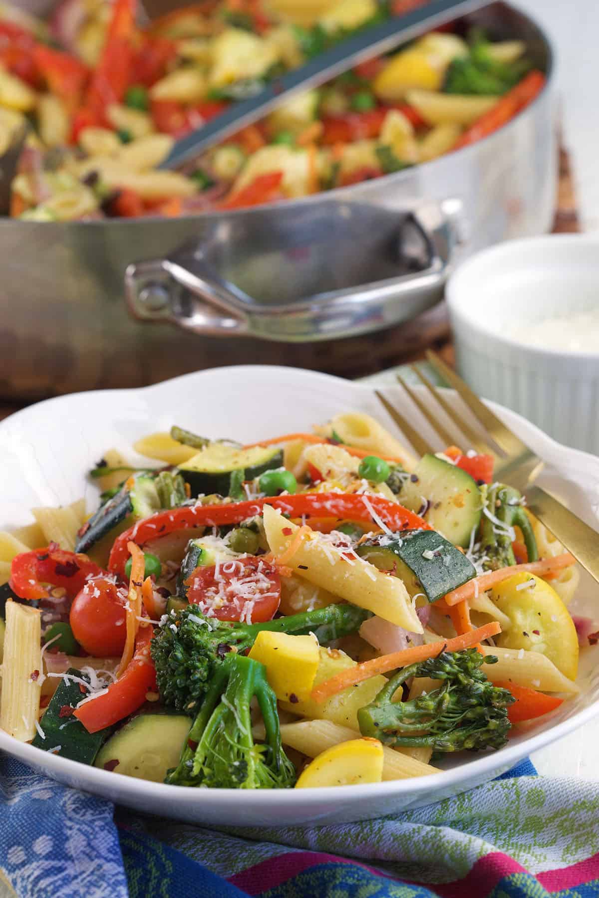 Pasta Primavera in a white bowl with a skillet in the background.