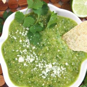 A chip is placed in a bowl of salsa verde.