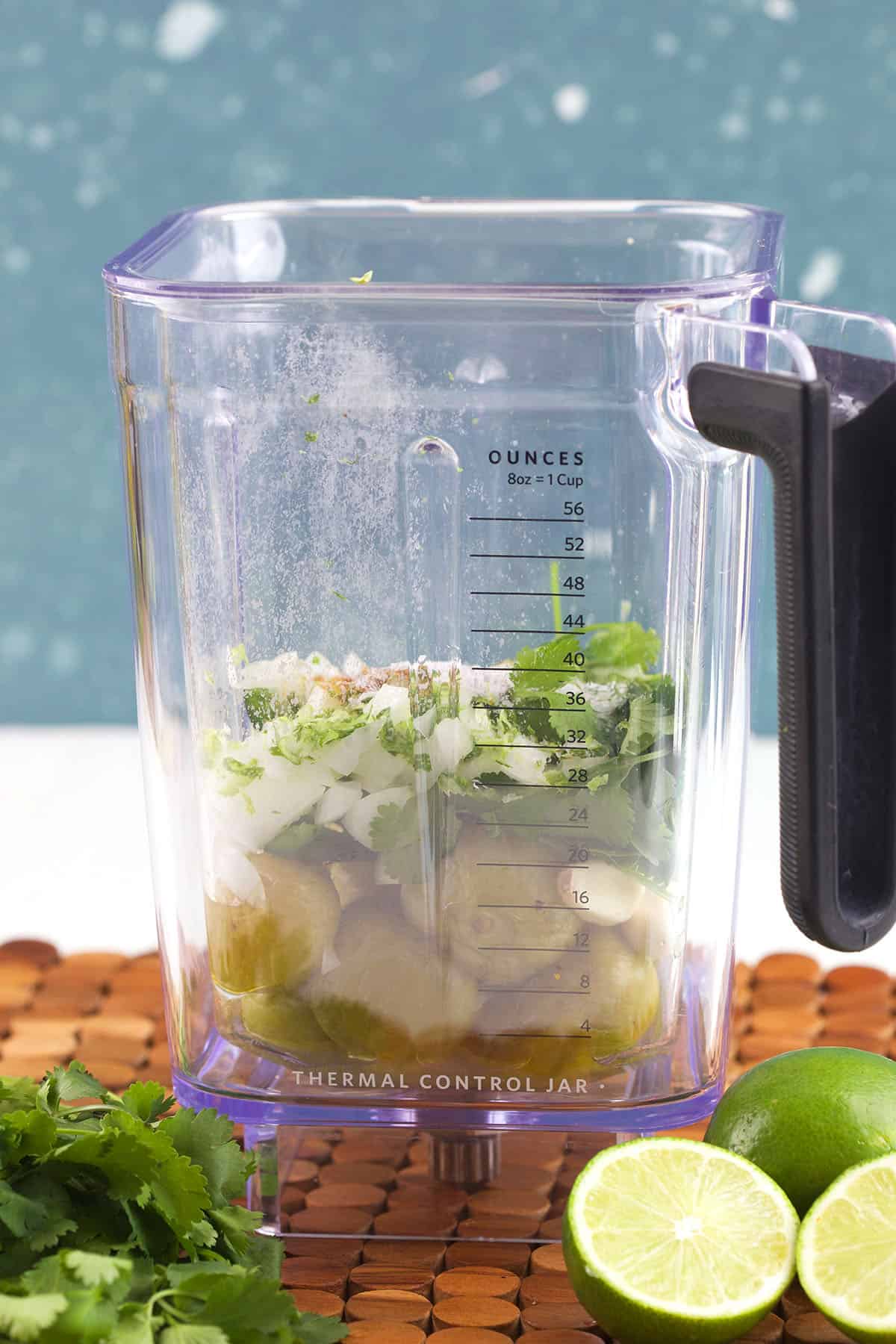 A blender is filled with salsa verde ingredients. 