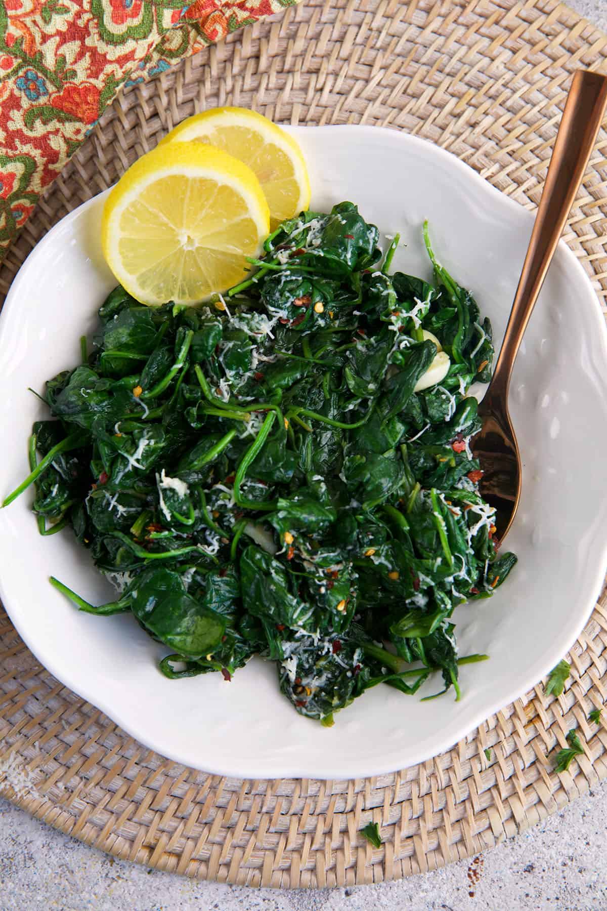 A white bowl is filled with sauteed spinach. 
