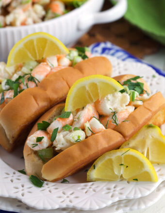 Two shrimp salad rolls are garnished with lemon wedges.
