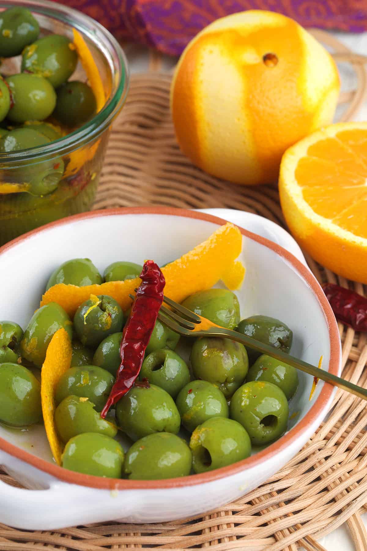 Orange peels and chili peppers are placed in a bowl of olives. 