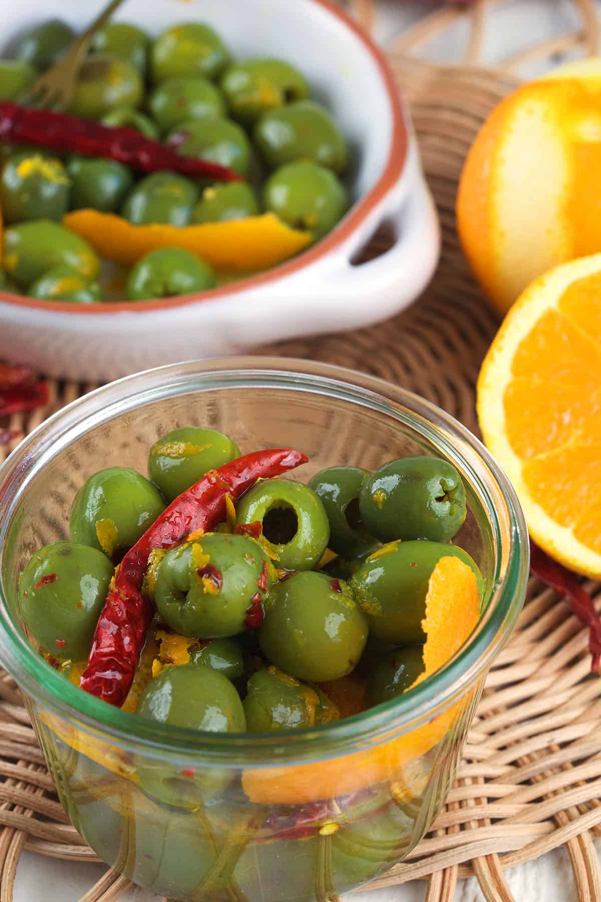 A small jar of olives is placed next to a larger bowl. 