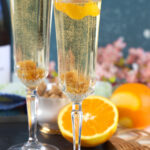 Two glasses are garnished with orange twists.