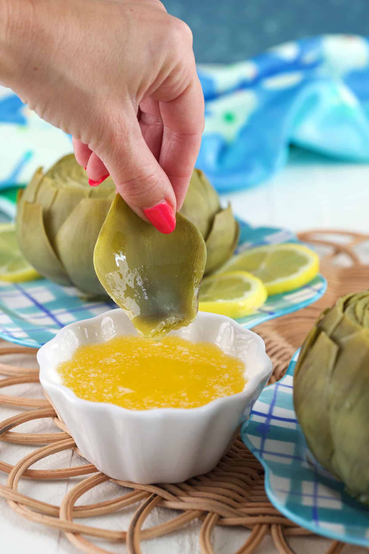 A single artichoke leaf is being dipped into butter. 