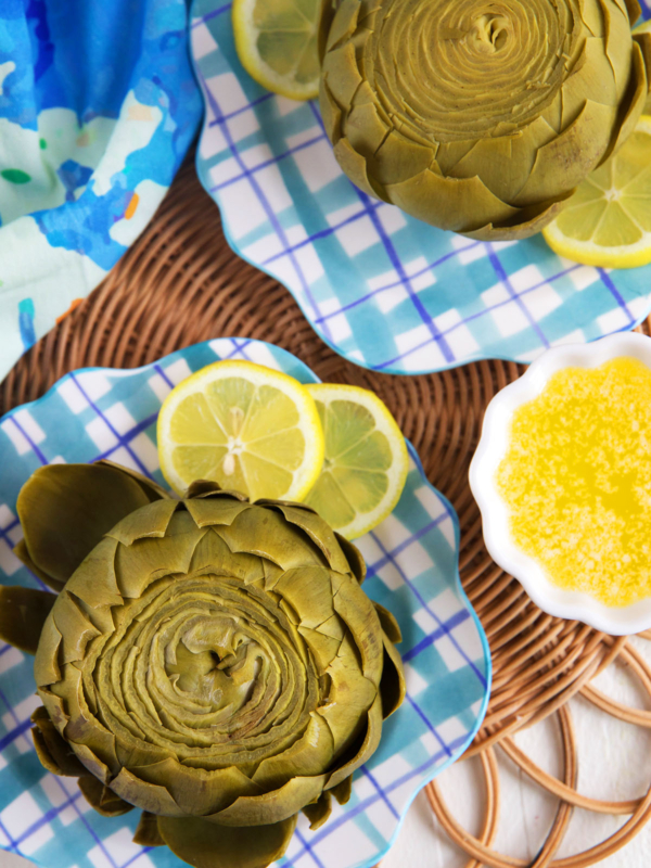 Plated artichokes are placed next to lemon slices.