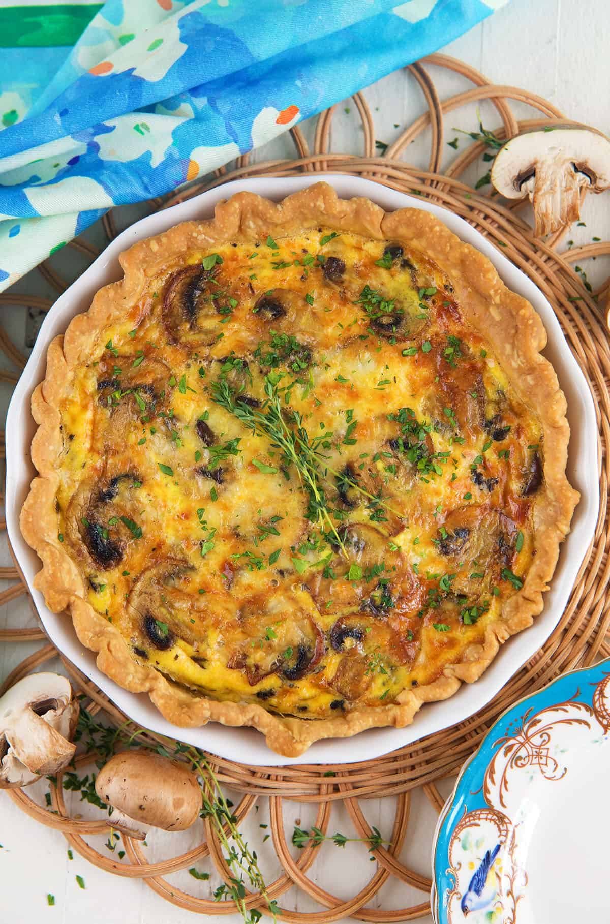 A baked mushroom quiche is garnished with fresh herbs. 
