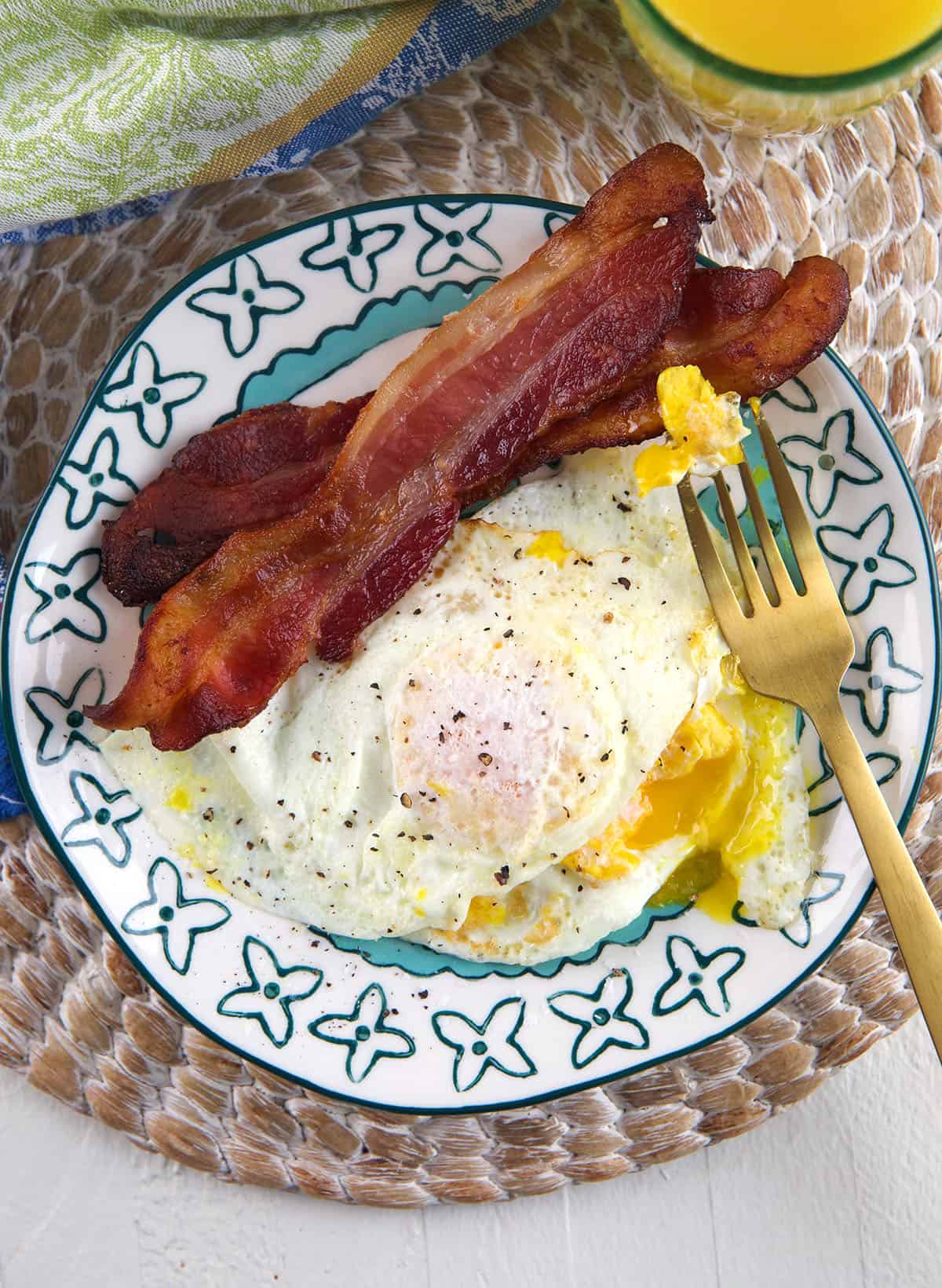 Bacon and eggs are on a plate. 