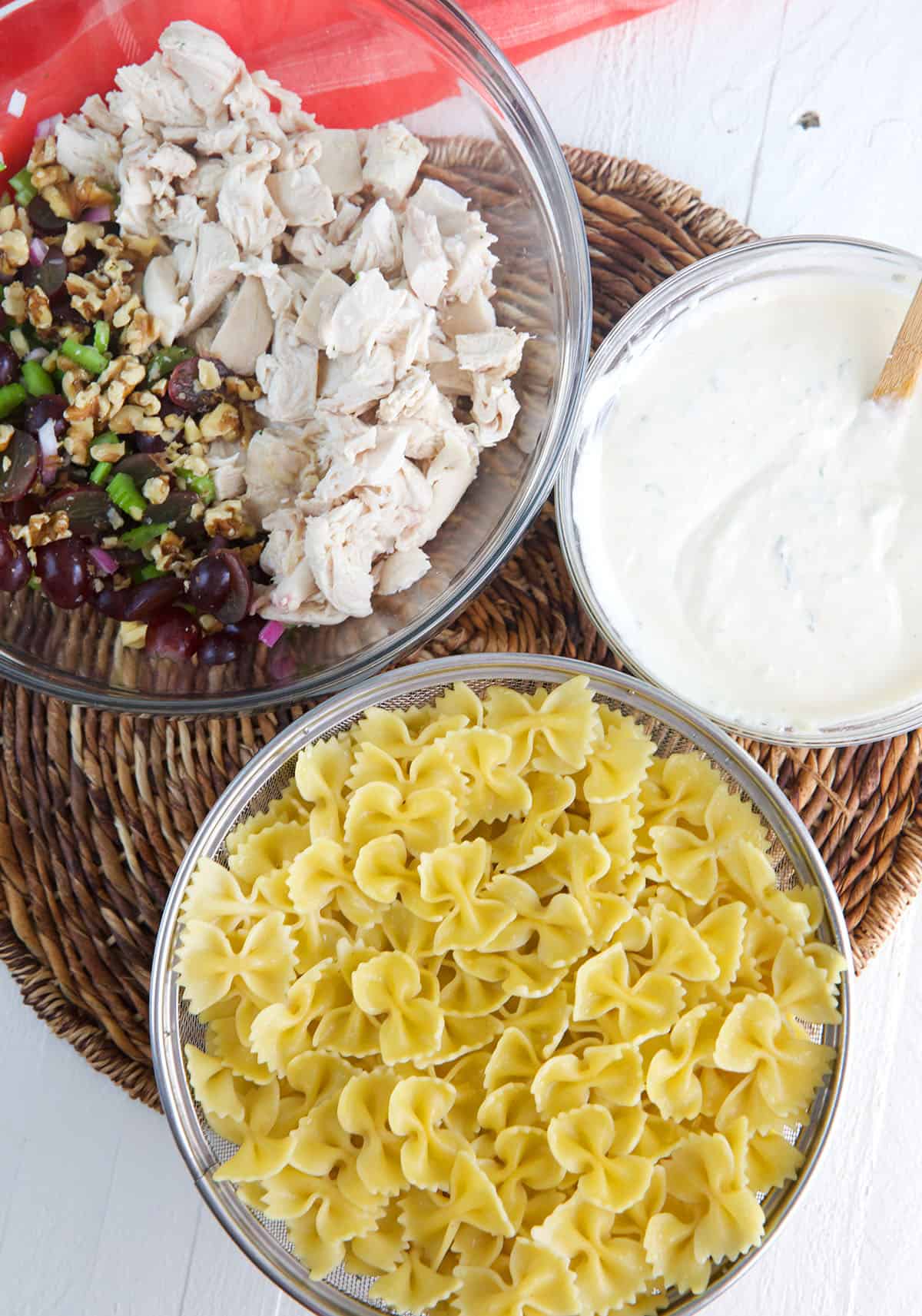 The ingredients for tarragon pasta salad are in separate bowls. 