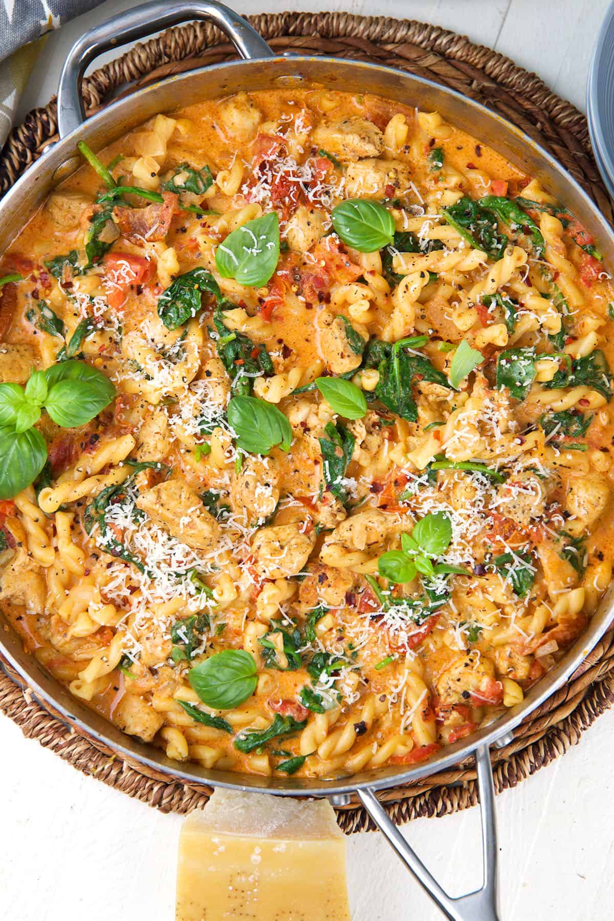 A skillet is filled with tuscan chicken pasta. 