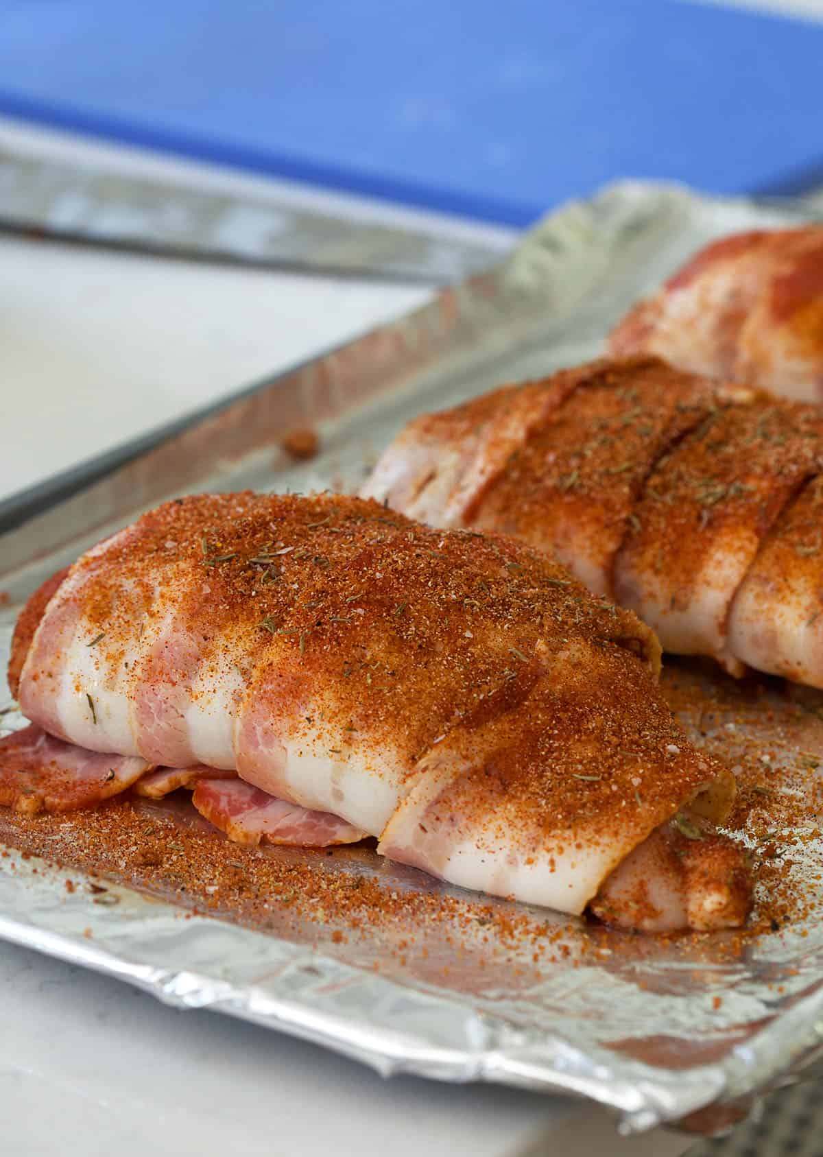 A bacon wrapped chicken breast is raw. 