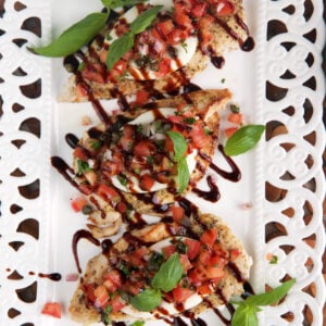 Three servings of bruschetta chicken are on a white plate.