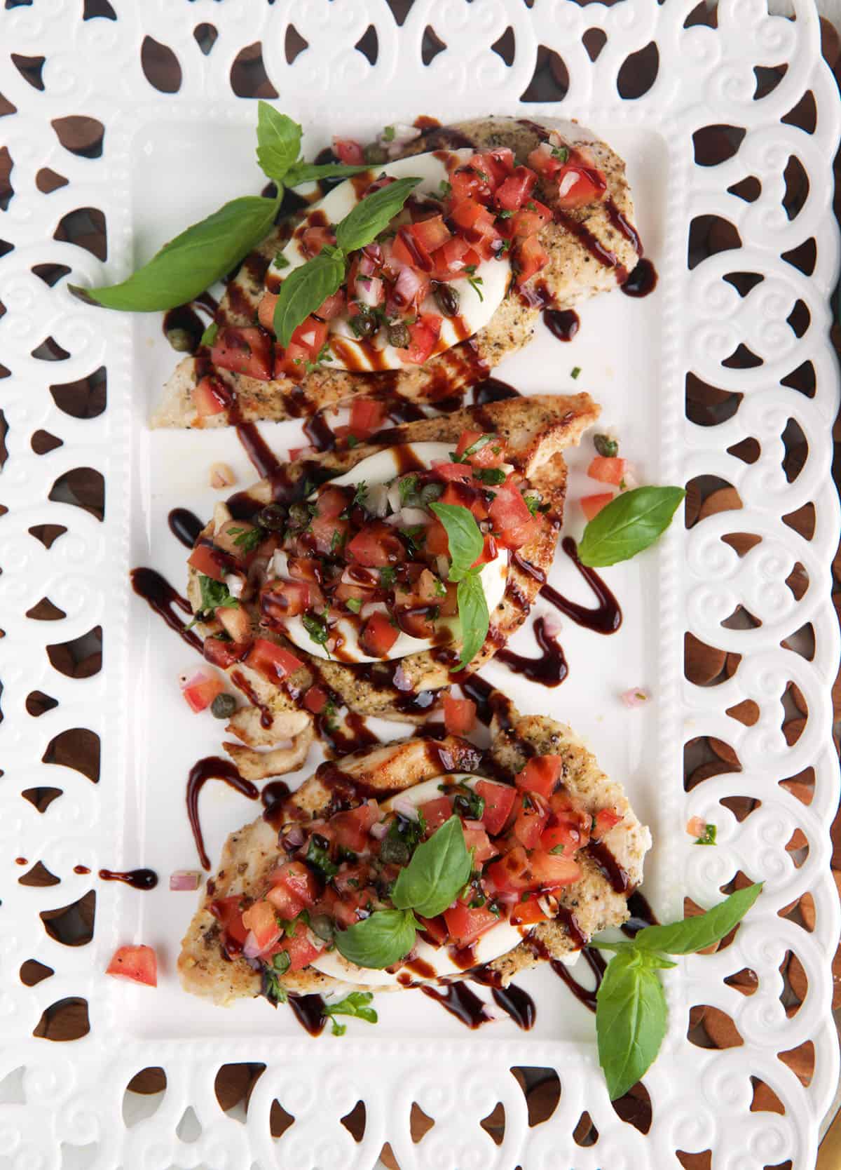 Three servings of bruschetta chicken are on a white plate. 