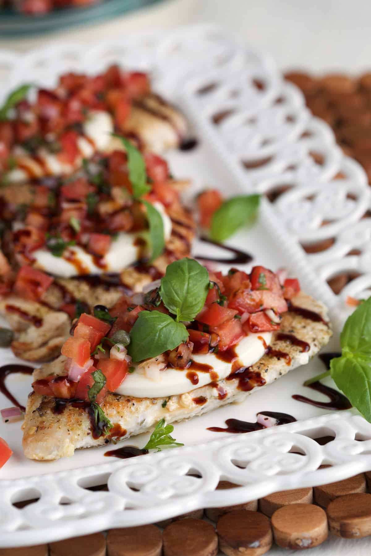 Several servings of bruschetta chicken are on a white plate. 