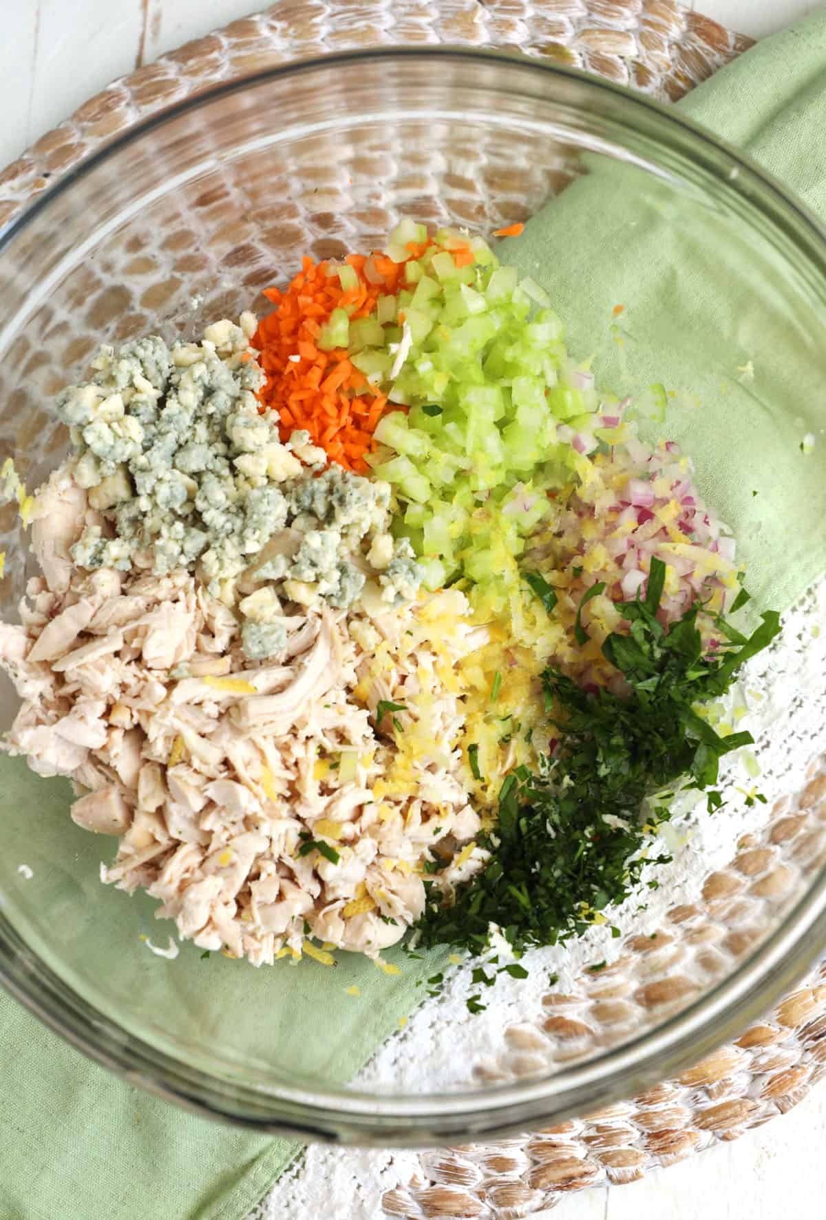 The ingredients for buffalo chicken salad are in a glass bowl. 