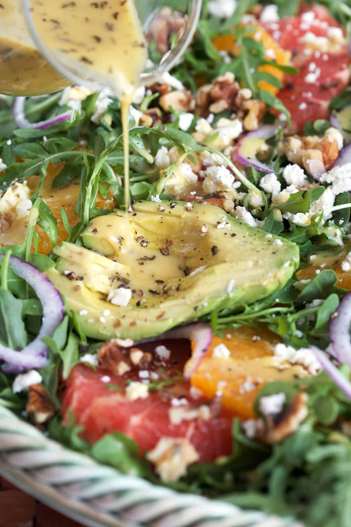 Dressing is being poured on top of a salad. 