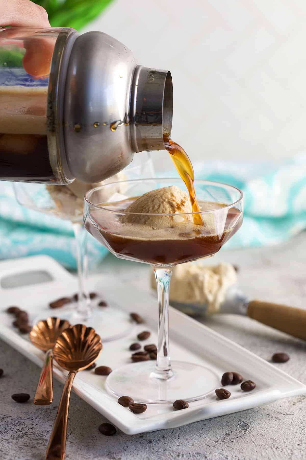 An espresso martini is being poured over ice cream in a glass. 