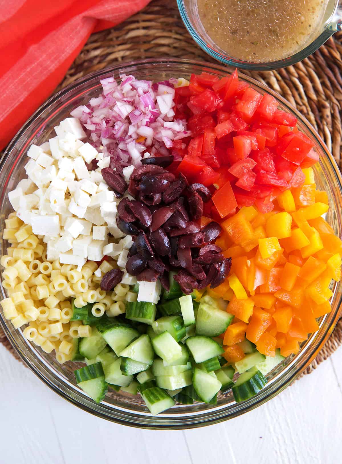 Greek pasta Salad ingredients in a glass bowl 