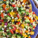 Greek Pasta Salad on a blue platter with a gold serving spoon in it.