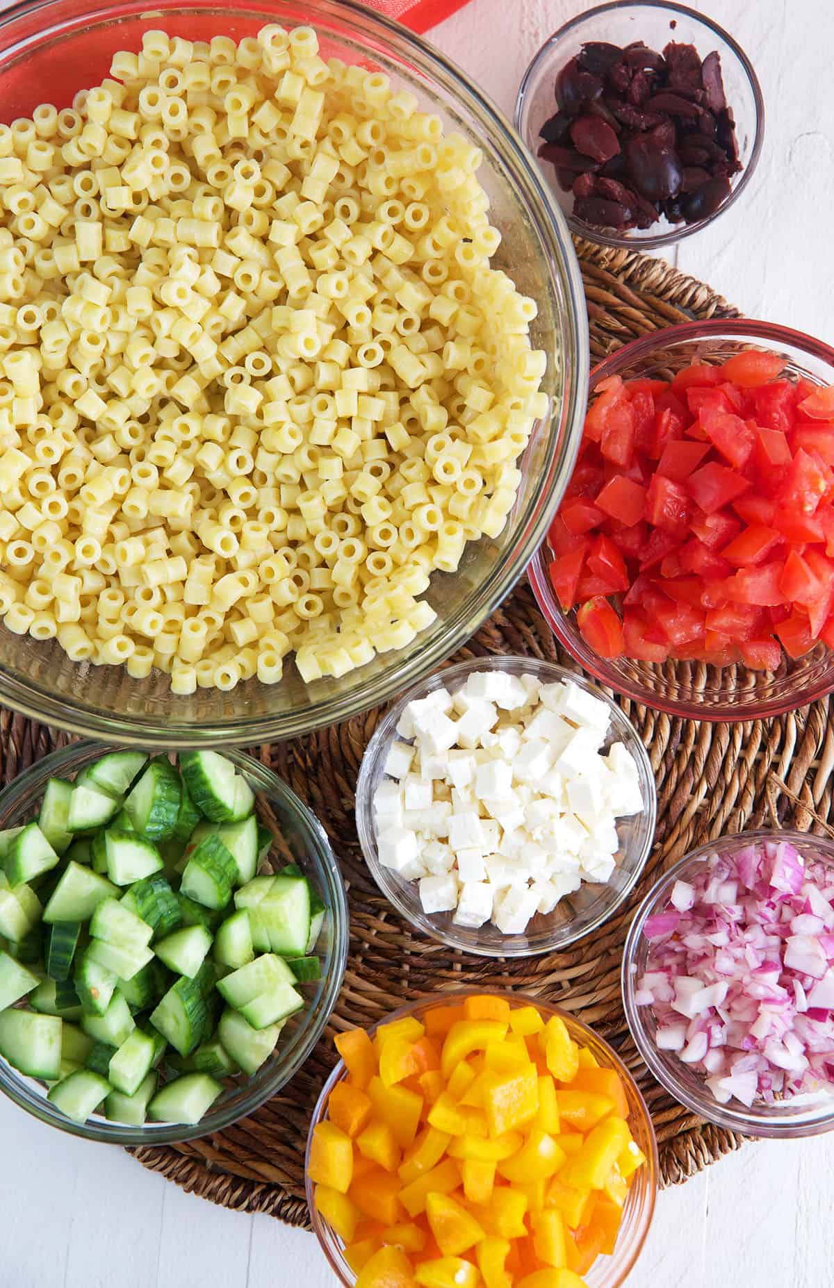 Ingredients for Greek Pasta Salad in glass bowls.