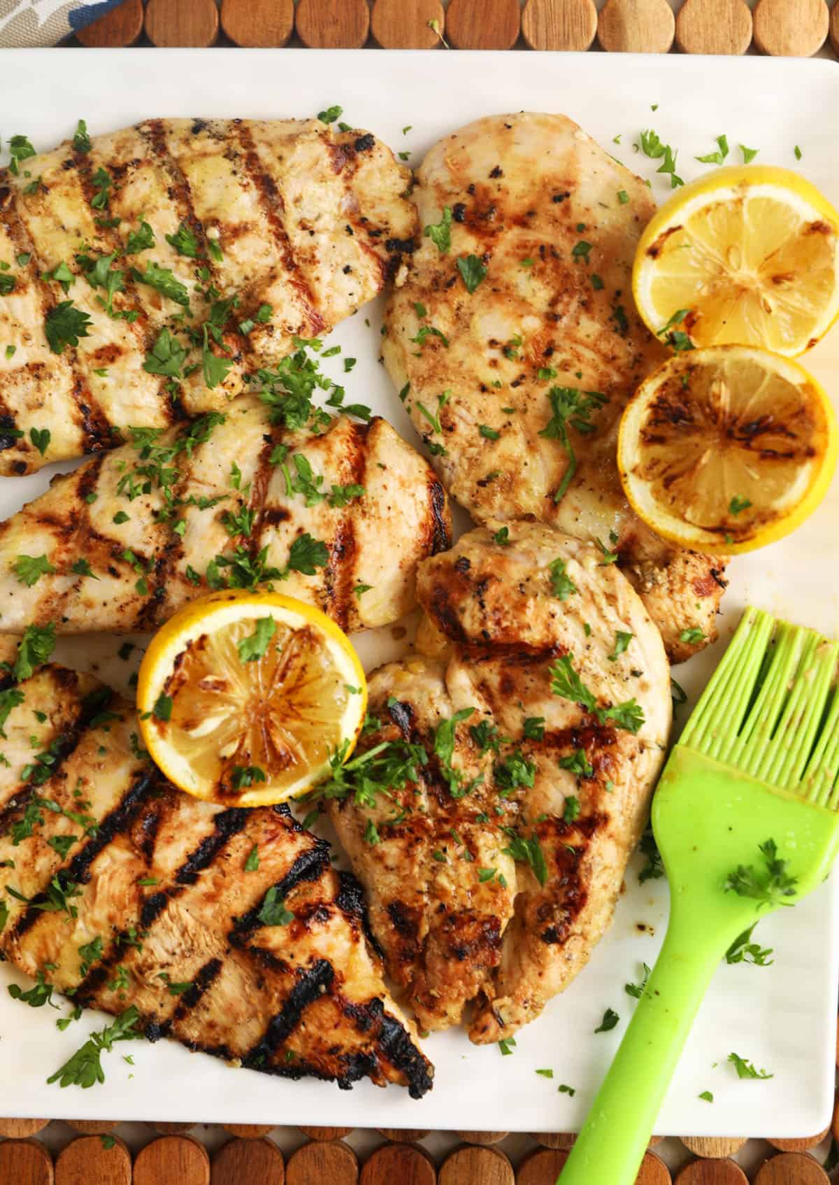 Grilled lemon chicken is presented on a white platter. 