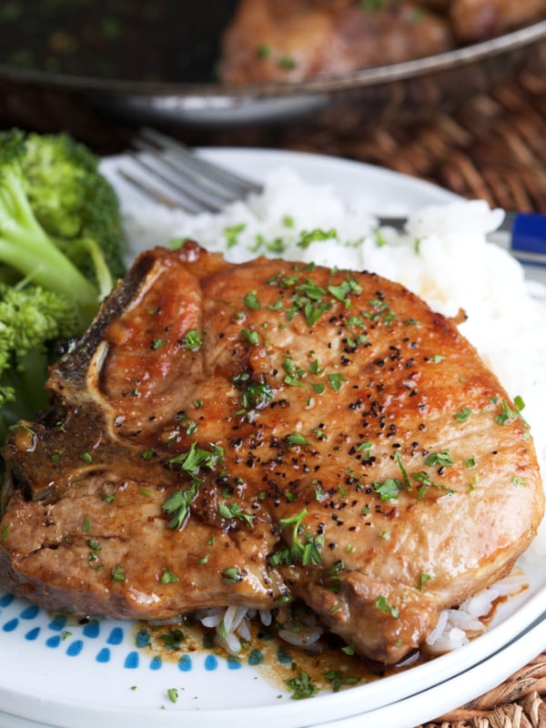 A plate is topped with pork chops and sides.