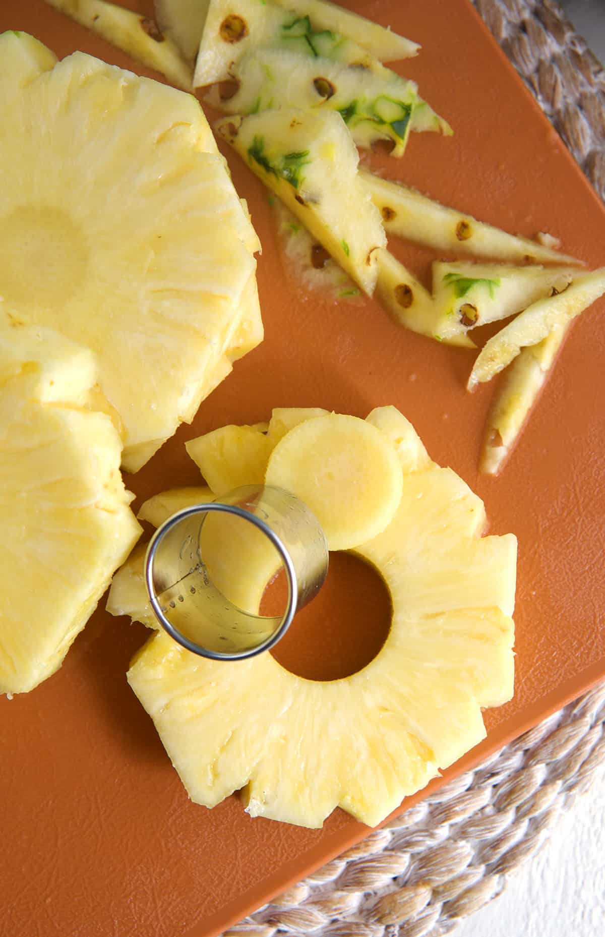 A biscuit cutter is creating pineapple rounds. 