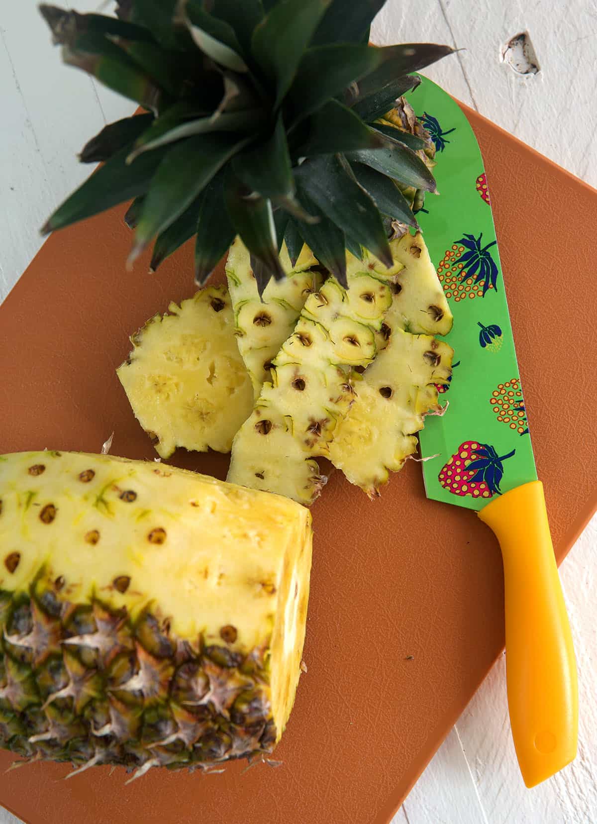 The rinds are being sliced off of a pineapple. 